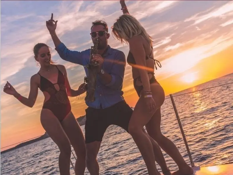 Happy party people celebrating with champagne and drinks at Oceanbeat Ibiza sunset boat party